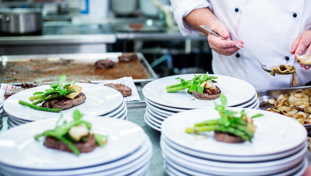 A chef prepares gourmet dishes in a professional kitchen setting, showcasing fine dining elegance.